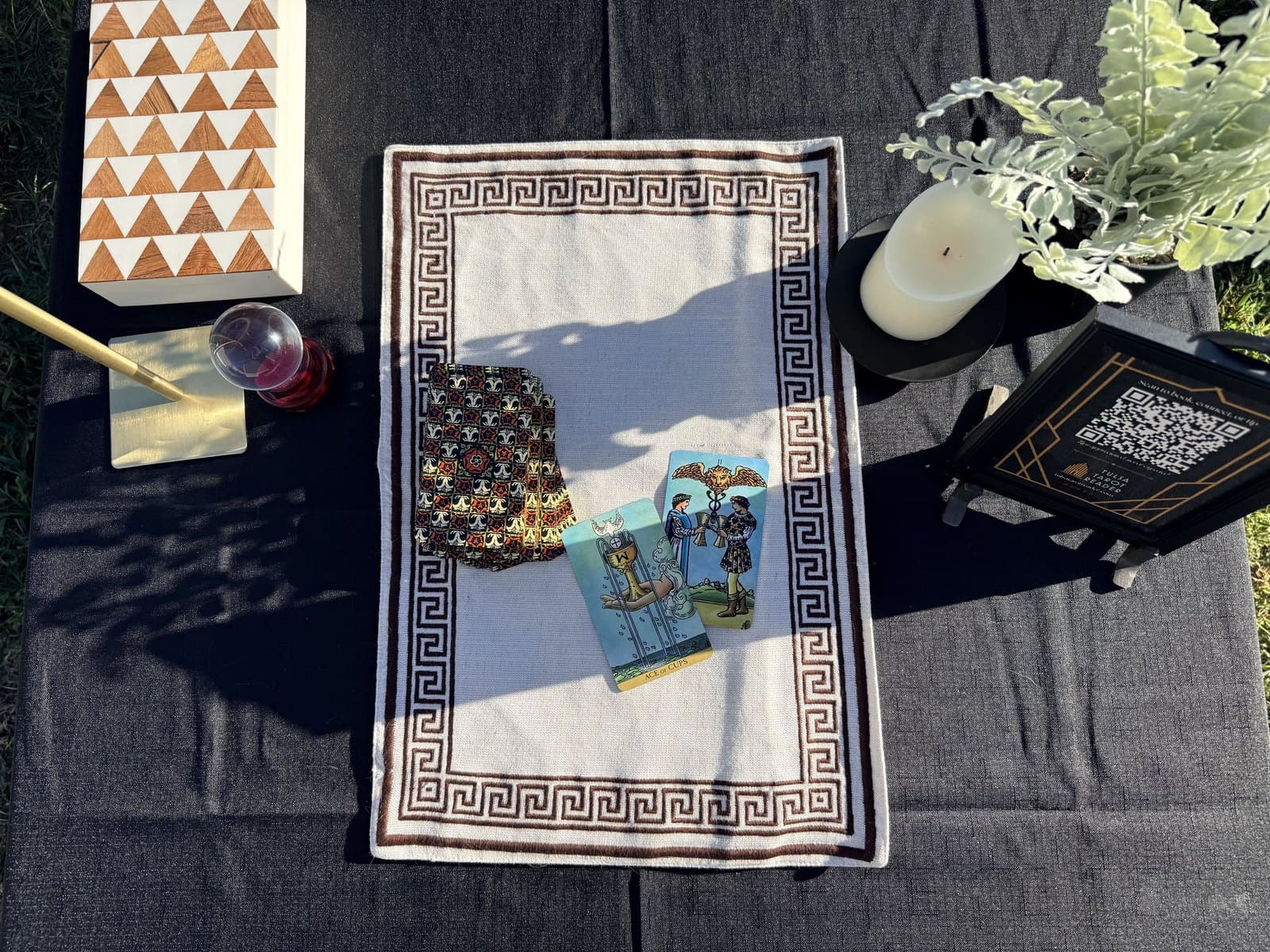 The deck and two drawn cards on the runner, beside the lamp and candle